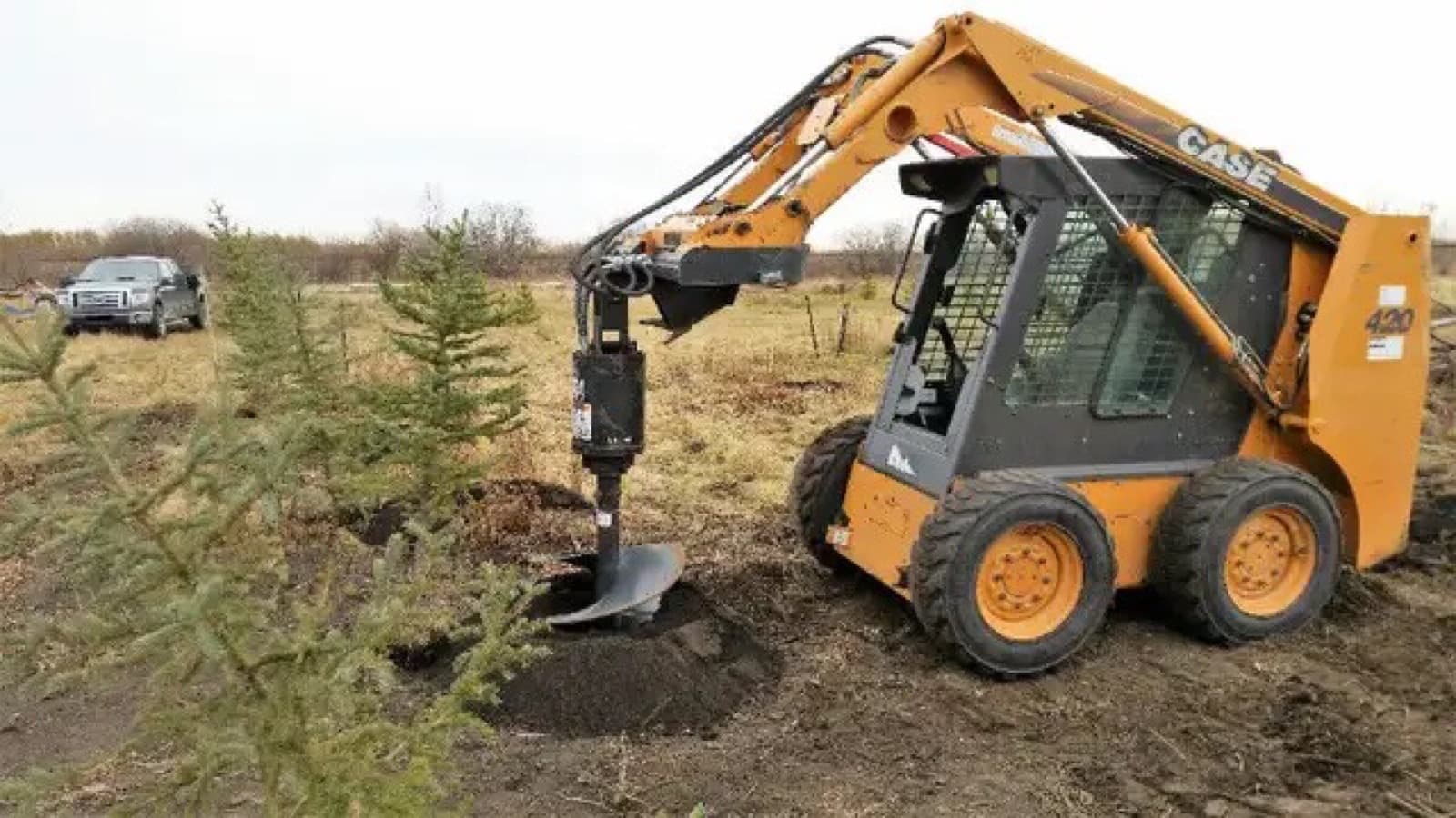 Skid steer drilling post holes with an auger