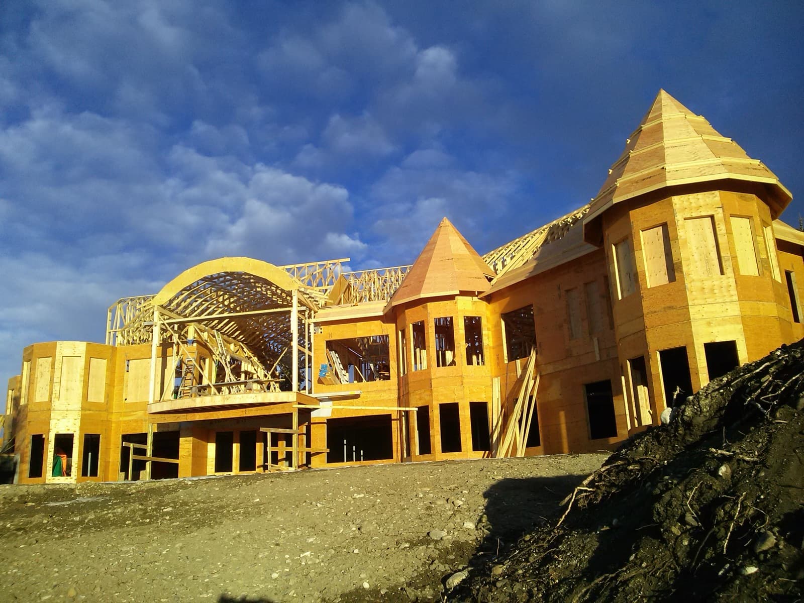 Large custom home being framed against a blue sky